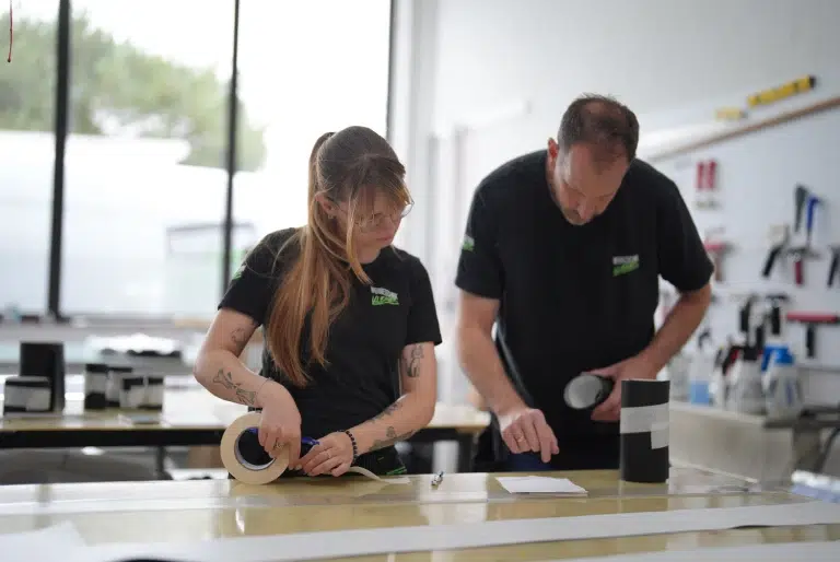 Teamarbeit bei der Verarbeitung von Druck- und Folienmaterialien in der Werkstatt von Werbetechnik Kleiner GmbH.