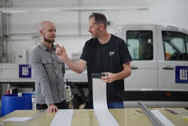 Fachliche Abstimmung und Projektbesprechung im Team von Werbetechnik Kleiner GmbH in der Produktionshalle.