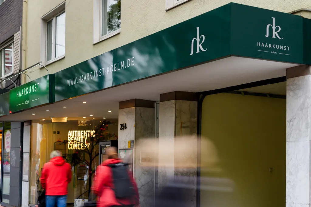 Straßenperspektive einer Ladenzeile mit markanter Außenwerbung und Markise, Werbetechnik Kleiner GmbH