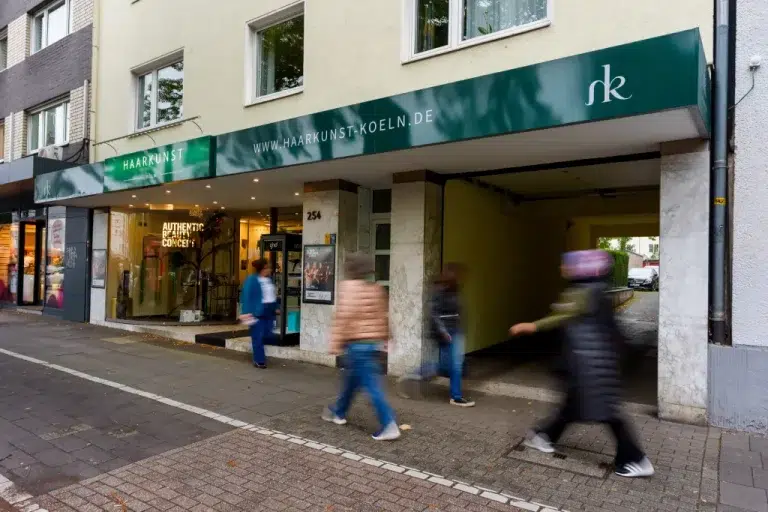 Ladenfront mit Markisenbeschriftung und Schaufenstergestaltung im urbanen Umfeld, gestaltet von Werbetechnik Kleiner GmbH.
